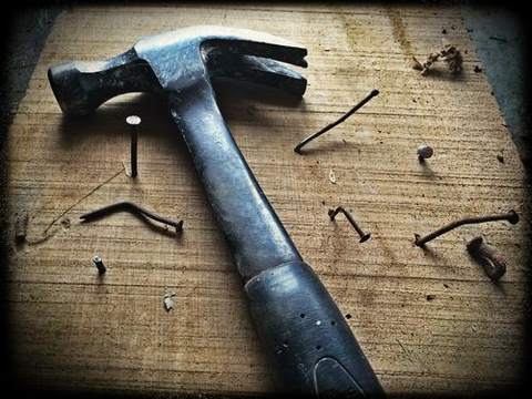 A hammer and hand tools laid out on a wooden workbench