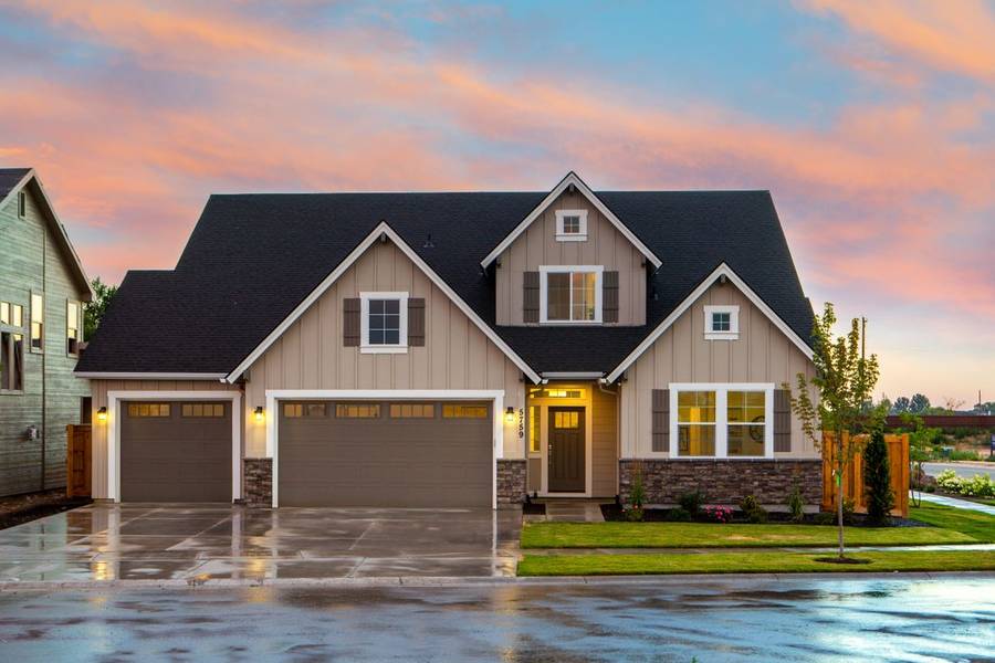 A beautiful two-story home at sunset with a pink and orange sky